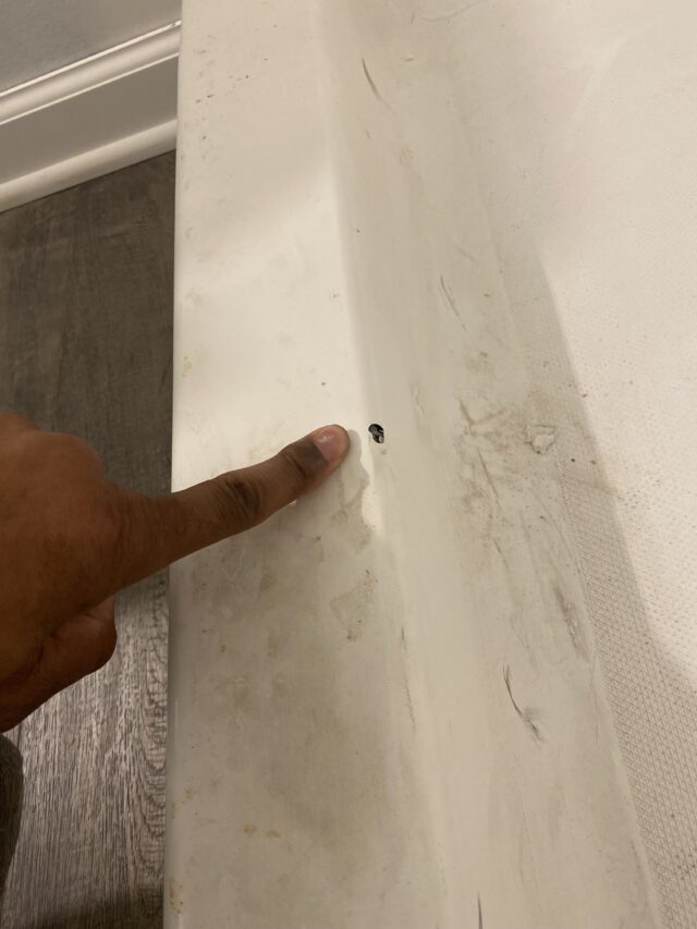 repair person pointing out the state of a dirty bathtub