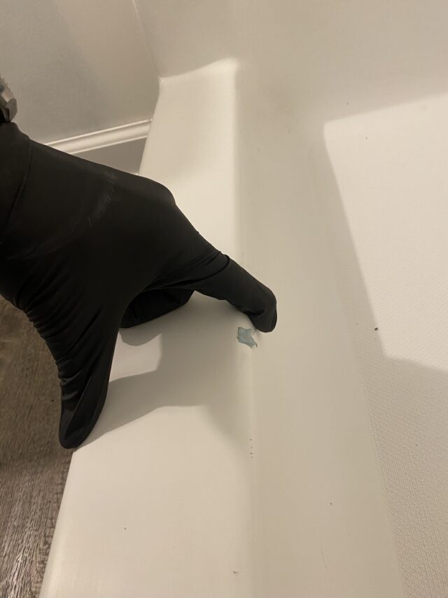 gloved hand putting small blue tac on tub