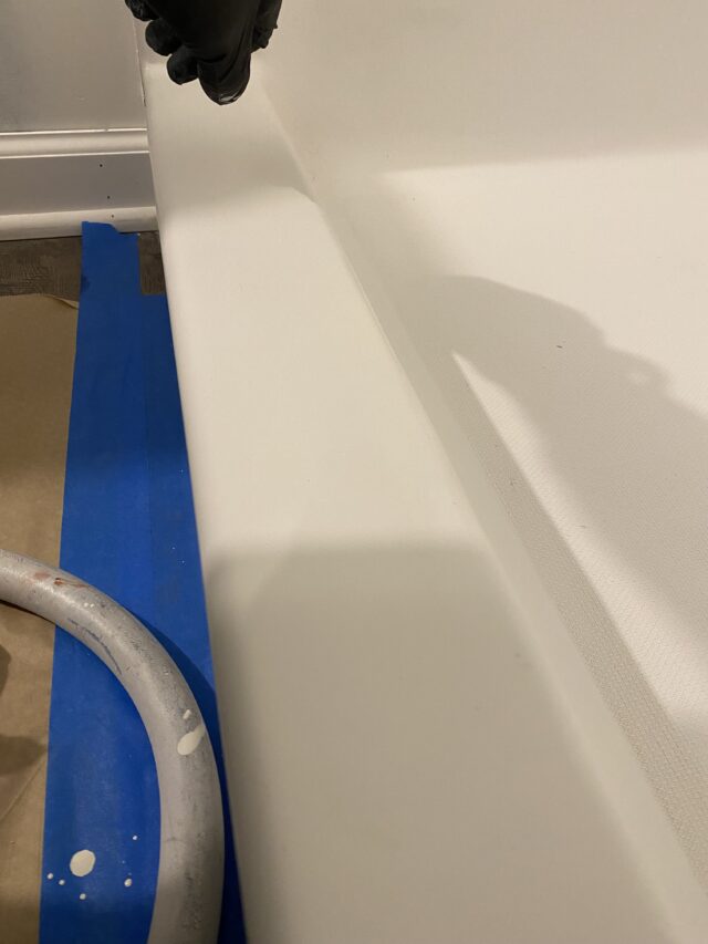 bathtub with blue tarp and metal hose